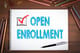 notebook with open enrollment written on it with office supplies on desk