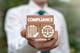 man holding wooden blocks that say compliance