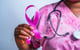 woman wearing pink scrubs holding a pink breast cancer ribbon