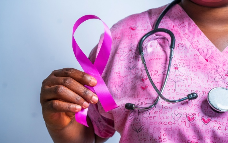 woman wearing pink scrubs holding a pink breast cancer ribbon woman wearing pink scrubs holding a pink breast cancer ribbon