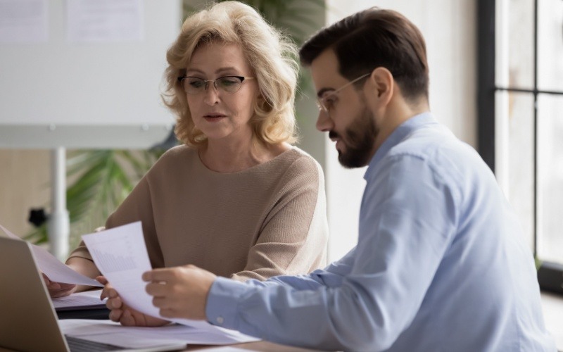 man and woman sitting at desk reviewing papers