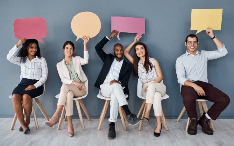 group of employees holding up word bubbles