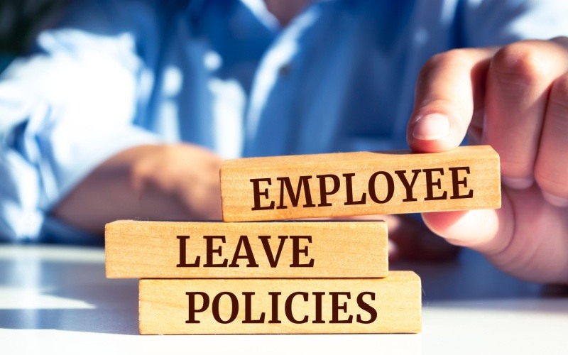 Man stacking wood blocks that reads employee leave policies