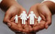 hands cupped together holding a paper doll family