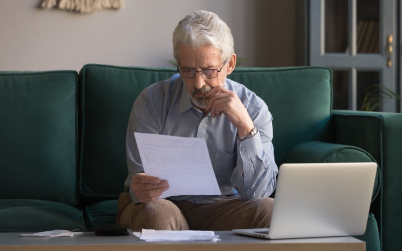 elderly man looking at paperwork and thinking