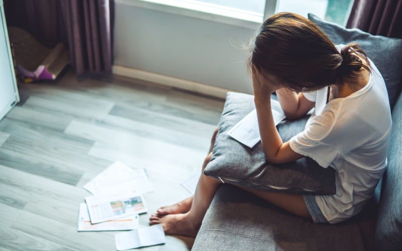 woman sitting with hand on head with lots of paperwork