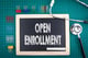 chalkboard that says open enrollment with stethoscope and paperclips