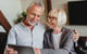 older couple hugging, smiling and looking at computer screen