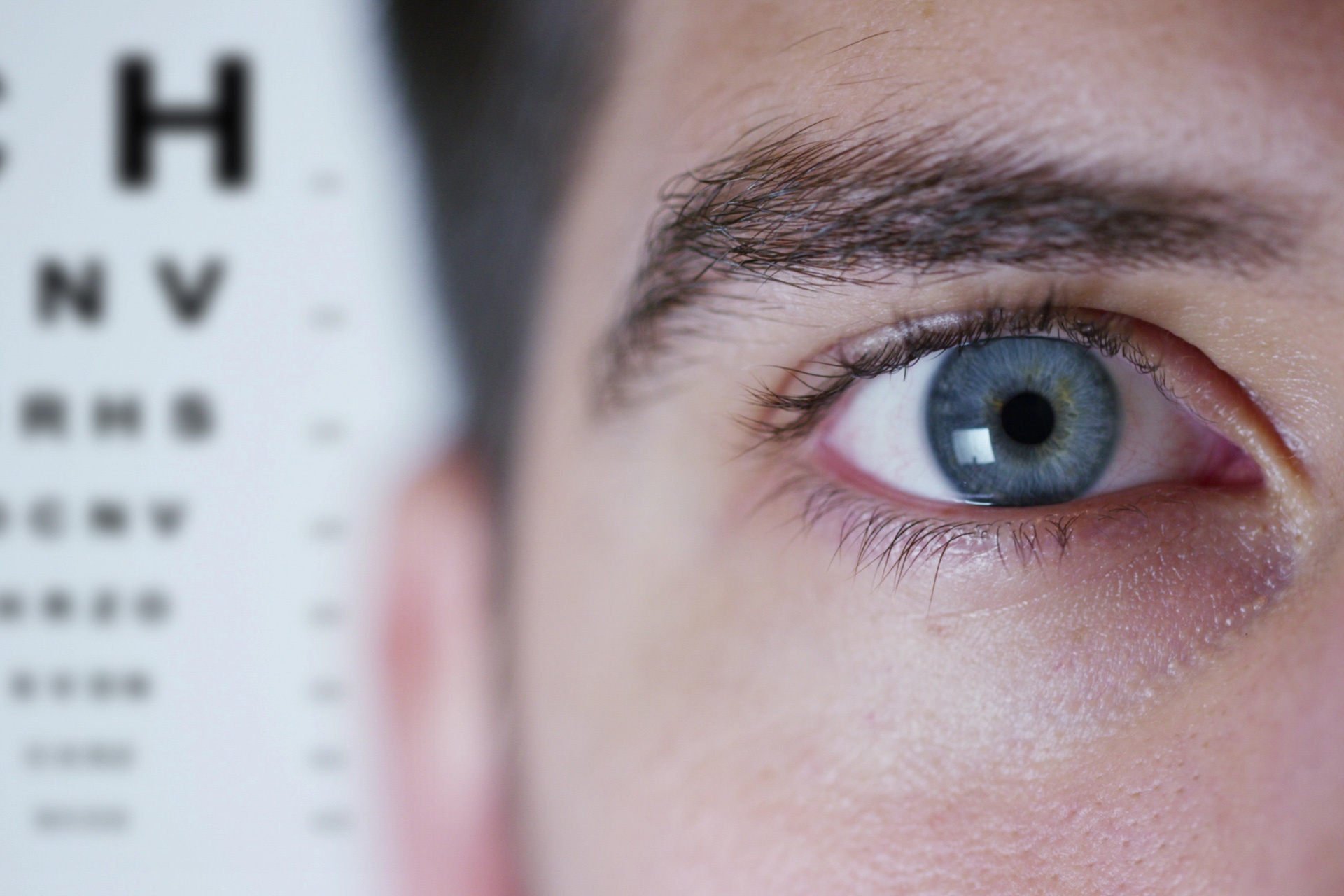 close up image of a person's eye with eye chart behind them
