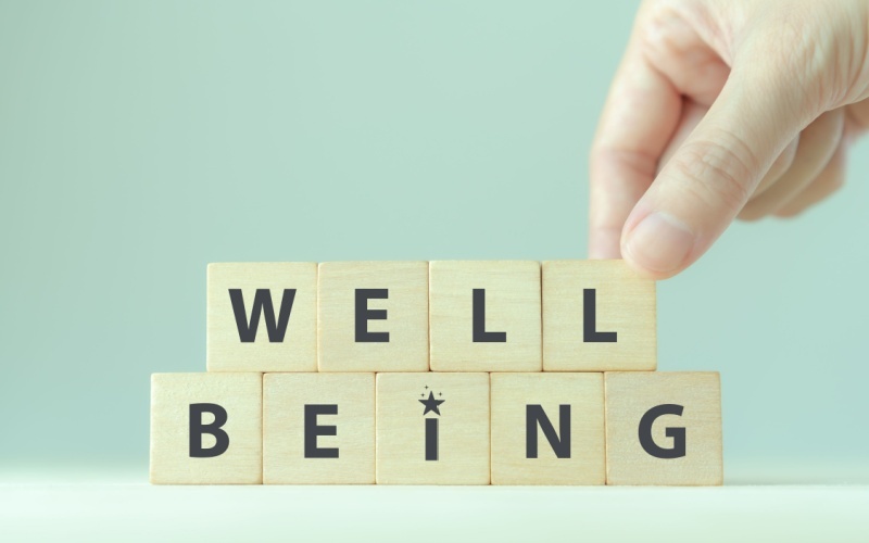 person setting up wood blocks that read well being