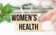 finger pointing to wood blocks on a desk that reads women's health