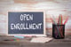 open enrollment witten on chalkboard with school supplies on desk 