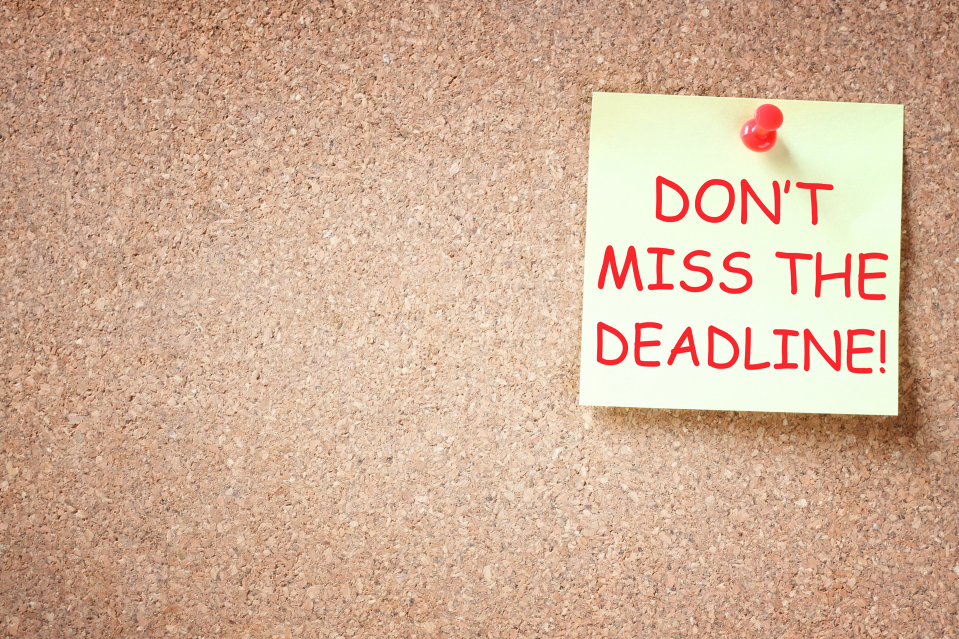 bulletin board with pinned note that says don't miss the deadline
