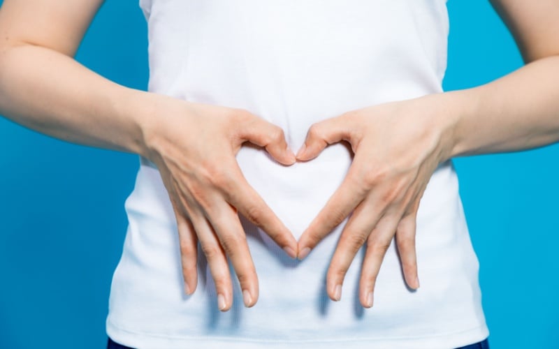 woman making heart with her hands over her stomach