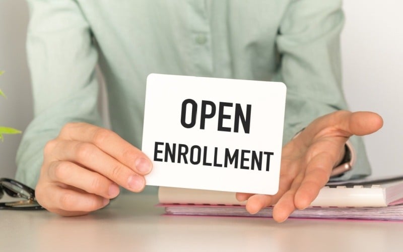 person holding sign that reads open enrollment