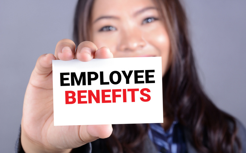woman holding up card that reads employee benefits