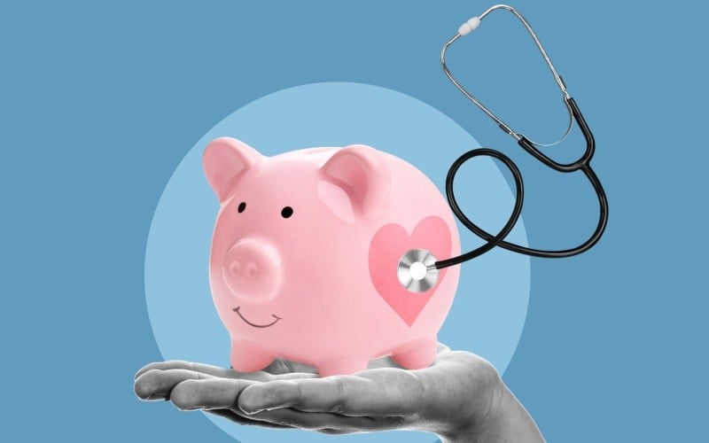 happy piggy bank sitting on hand with a stethoscope