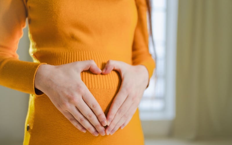 woman making heart with hands over stomach