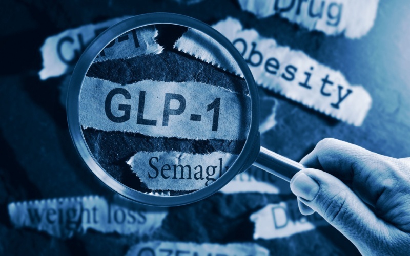 GLP-1 related drugs newspaper headlines with hand and magnifying glass