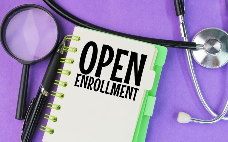 notebook that says open enrollment with magnifying glass and stethoscope