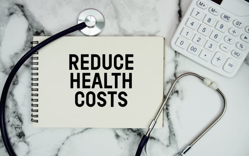 Reduce Health Costs text written on notepad with stethoscope and calculator