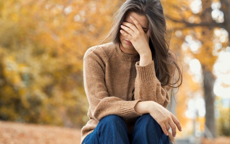 young woman holding her hand to her head looking stressed