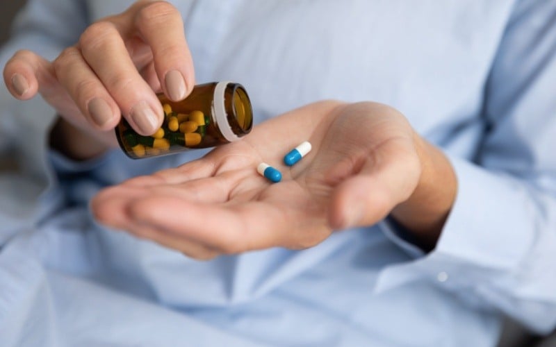 person holding prescription pill bottle with pills in their hand